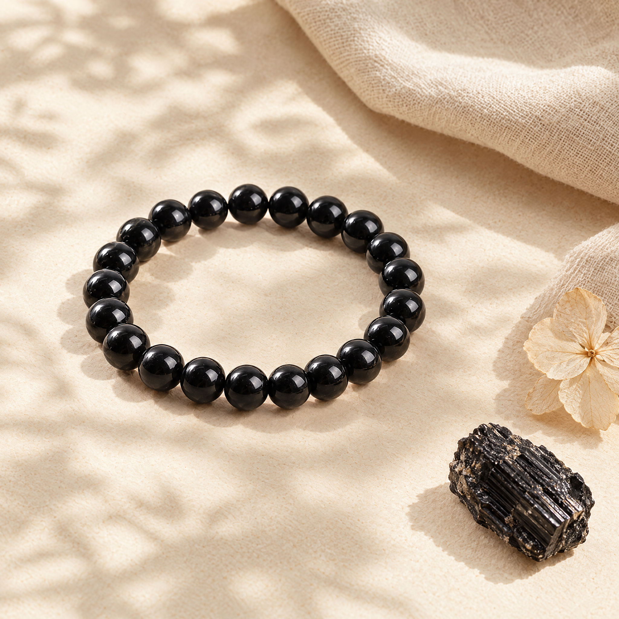 The black tourmaline bracelet in a soft flat-lay with linen and natural stone